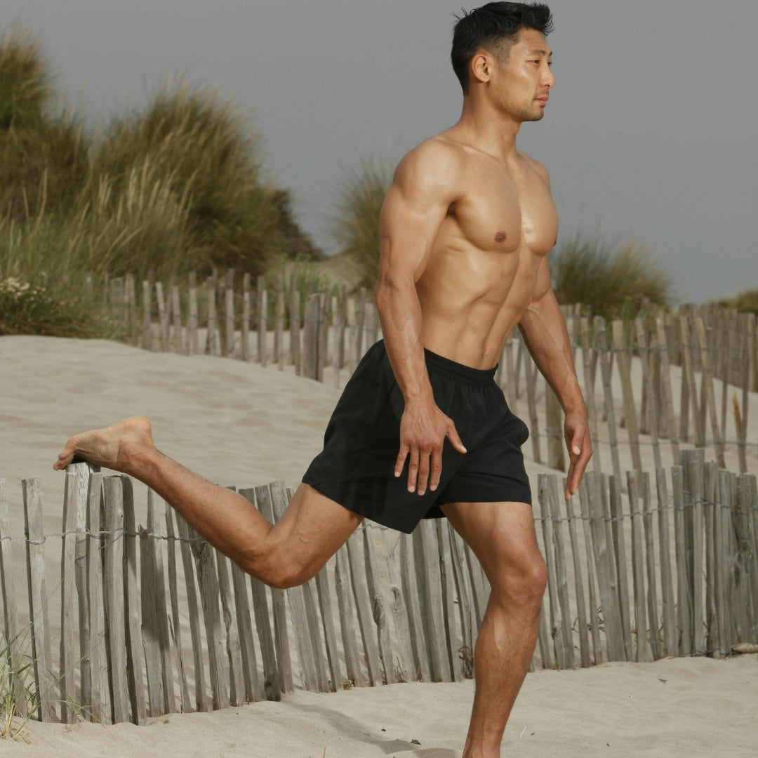 Man running on a sandy path with grass and wooden fence in the background